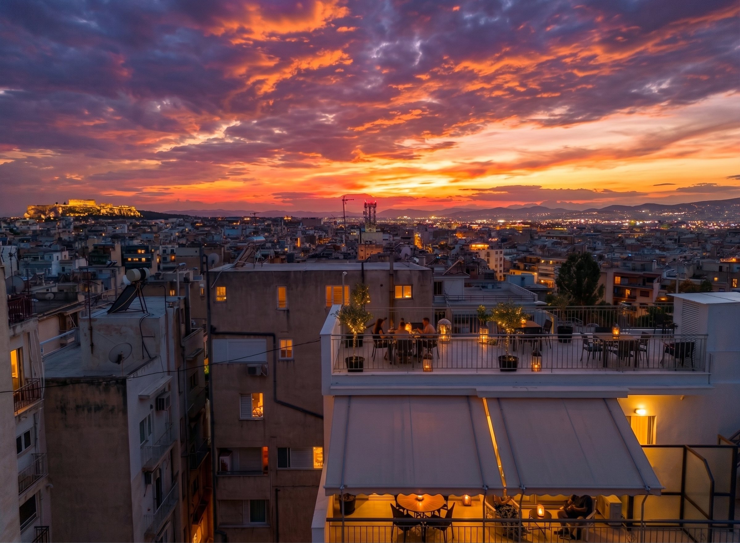 Guests dining on the shared rooftop at sunset, the Acropolis lit on the horizon