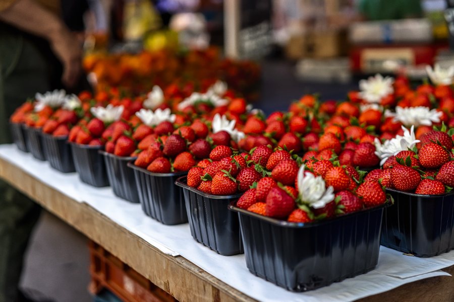 Punnets of strawberries laid out with white flowers on a stall at the Kallidromiou Street market