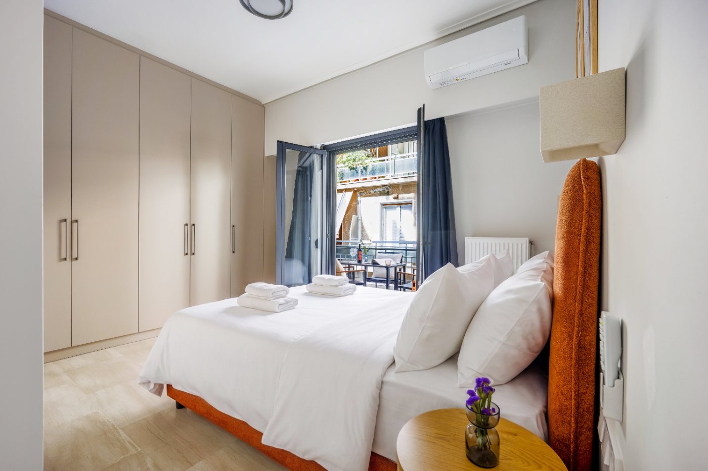 An upper-floor bedroom with full-height wardrobes and its balcony doors open